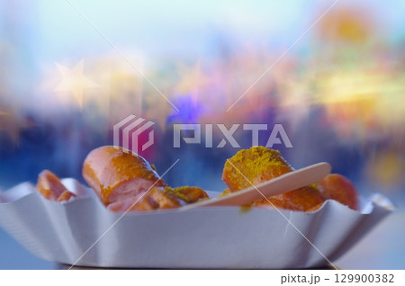Plate of hot dogs with mustard and a wooden stick 129900382