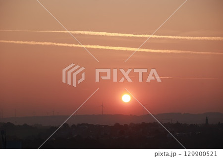 The sun is setting over a city with a beautiful orange sky The sun is setting over a city with a beautiful orange sky 129900521