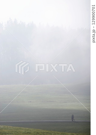 Person is walking in a field with foggy weather Person is walking in a field with foggy weather 129900701