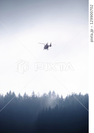 Helicopter is flying over a forest 129900702