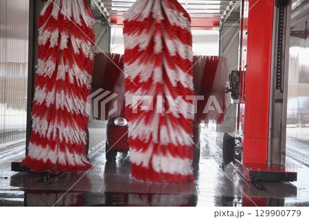 Car is being washed with a red and white brush 129900779