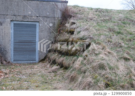 A concrete structure with a metal grate on the door 129900850