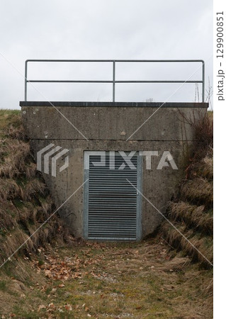 A small, narrow tunnel with a metal grate door 129900851