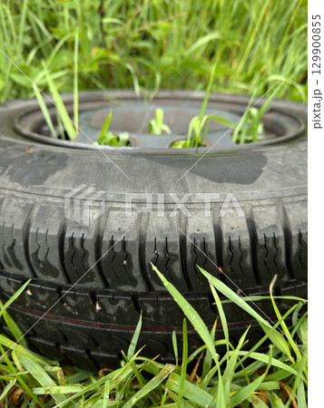 Tire is sitting in the grass 129900855