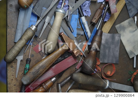 Table full of woodworking tools, including hammers, pliers, and knives 129900864