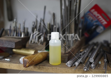 Bottle of oil sits on a shelf next to a bunch of tools 129900865