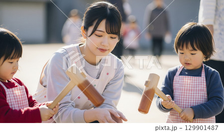 保育士と園児たちが餅つきを楽しむ 129901487