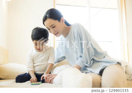 寝転んでスマホを見る子供 129901535