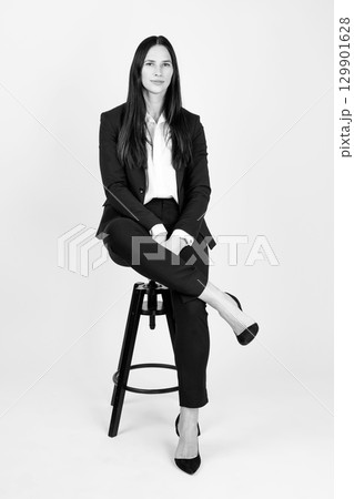 Beautiful woman with classic outfit sitting on chair studio portrait 129901628