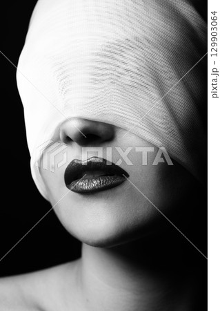 Beautiful woman portrait hiding her eyes under white ribbon, cloth or fabric 129903064