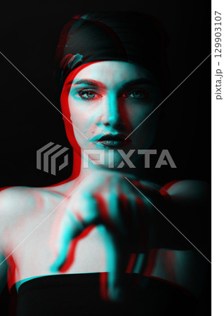 Studio portrait of beautiful woman with scarf on her head pointing finger to camera in RGB color split effect 129903107