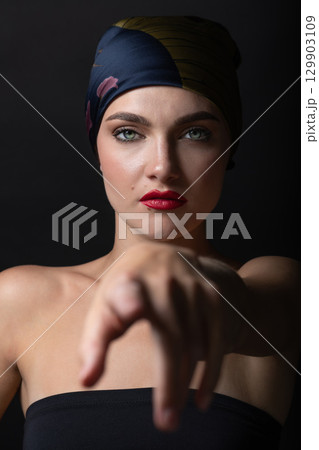 Woman with make-up and scarf on her head studio portrait Woman with make-up and scarf on her head studio portrait 129903109