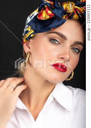 Woman with make-up and scarf on her head studio portrait 129903111