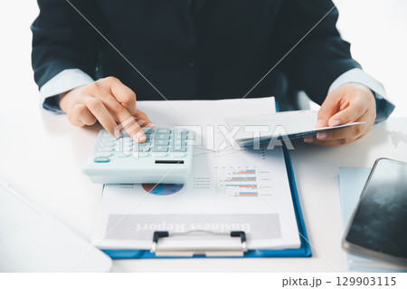 Business hands holding saving account passbook with calculator, account and saving concept. finance effectively, calculate income, track each bill and payment, accounting for bank statements and tax. Business hands holding saving account passbook with calculator, account and saving concept. finance effectively, calculate income, track each bill and payment, accounting for bank statements and tax. 129903115