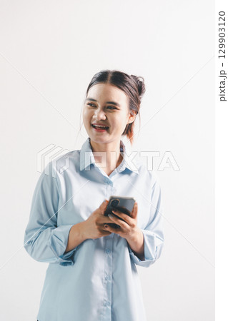 Asian woman rejoicing, looking happy, champion, fist pump gesture, standing over white background. young woman had happy, positive expression on her face, highlighted by bright smile. 129903120