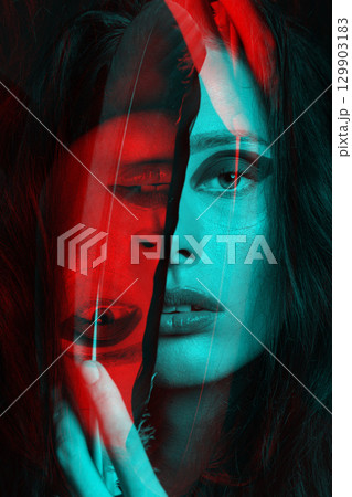 Studio portrait of woman covering one eye with big bird feather in RGB color split effect style 129903183
