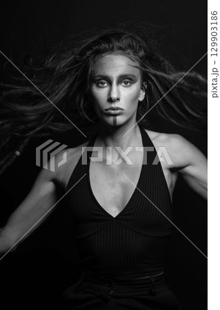 Model with make-up and hair with dreadlocks jumping in air and looking at camera 129903186