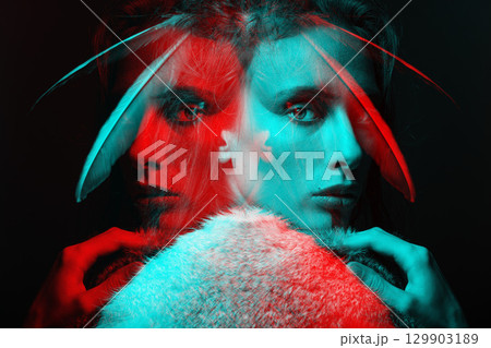 Studio portrait of woman with dreadlocks and feathers in hair in RGB color split effect style 129903189