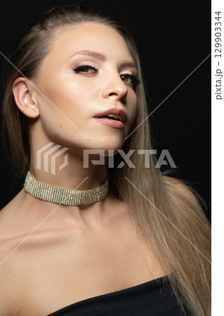 Beautiful brunette woman with black dress and fancy jewelry studio portrait 129903344