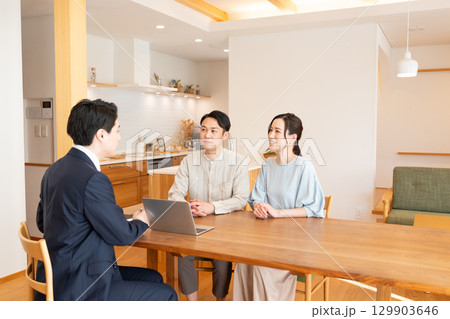 リビングで商談するビジネスマンと若い夫婦 129903646