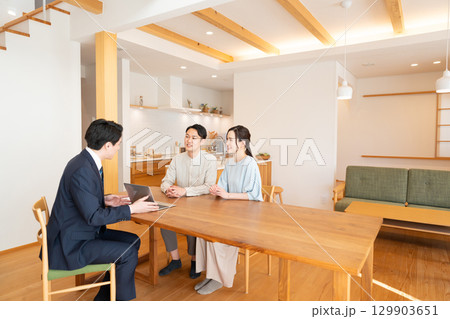 リビングで商談するビジネスマンと若い夫婦 129903651