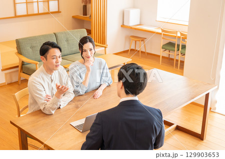 リビングで商談するビジネスマンと若い夫婦 129903653