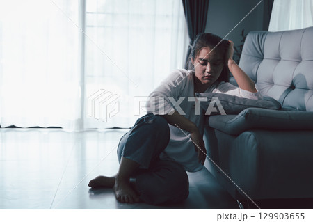 Tired depressed desperate tired girl sadly sitting on couch at home. Young woman is sitting on floor living room, feeling sad and depressed. Psychological problem. Depression and loneliness concept. Tired depressed desperate tired girl sadly sitting on couch at home. Young woman is sitting on floor living room, feeling sad and depressed. Psychological problem. Depression and loneliness concept. 129903655