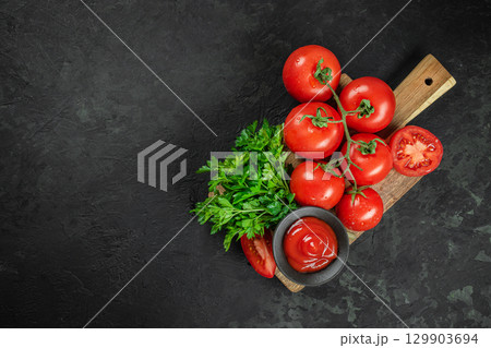 Fresh tomatoes with parsley and ketchup on wooden board. top view. copy space Fresh tomatoes with parsley and ketchup on wooden board. top view. copy space 129903694