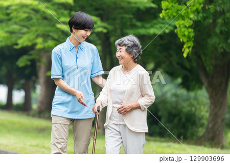 歩行杖を使うシニア女性と介護士 歩行杖を使うシニア女性と介護士 129903696