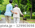 杖を使うシニア女性と介護士の後ろ姿 129903698