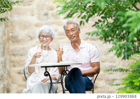 ベンチに座ってお茶を飲むシニア夫婦 129903868