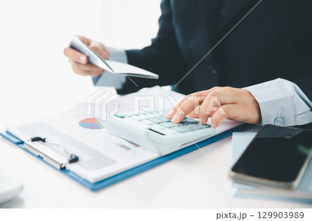 Business hands holding saving account passbook with calculator, account and saving concept. finance effectively, calculate income, track each bill and payment, accounting for bank statements and tax. Business hands holding saving account passbook with calculator, account and saving concept. finance effectively, calculate income, track each bill and payment, accounting for bank statements and tax. 129903989