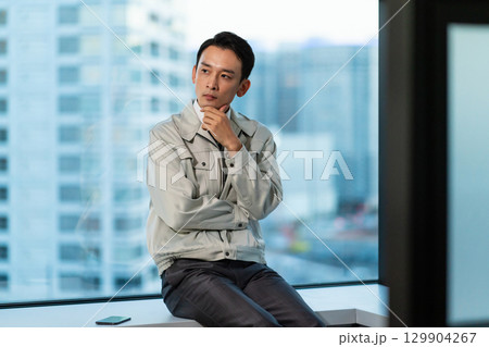高層ビルを見ながら考える作業着の男性 高層ビルを見ながら考える作業着の男性 129904267