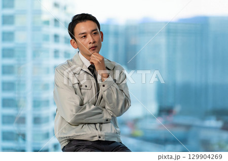 腕組みをして考える作業着の男性 129904269