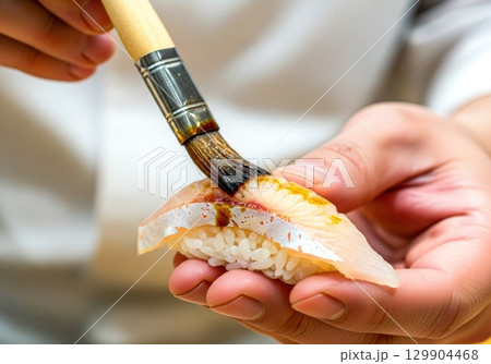 ぶりの握り寿司にハケでタレを塗る寿司職人 129904468