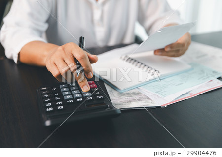 Using calculating machine, household carefully manages each bill and expense to plan financial budget, ensuring timely payment, consistent saving, smart investment for secure home finance strategy. 129904476