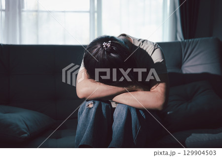 Depression woman sit on sofa. Despair sorrow person sitting alone and hugging knees, Boring sad upset frustrated stressed. struggling to find hope amid suffocating burden. mental health concept. Depression woman sit on sofa. Despair sorrow person sitting alone and hugging knees, Boring sad upset frustrated stressed. struggling to find hope amid suffocating burden. mental health concept. 129904503
