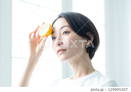 窓際でレモンを手に持つ透明感のある女性 顔のアップ 129905207