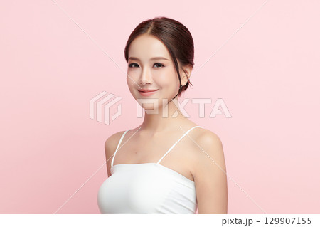 A beautiful young Asian woman with clean, fresh skin against a pink background. Skincare, facial treatment, cosmetology, beauty, and spa. An elegant portrait of an Asian woman. A beautiful young Asian woman with clean, fresh skin against a pink background. Skincare, facial treatment, cosmetology, beauty, and spa. An elegant portrait of an Asian woman. 129907155