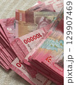 Abundant Pile of Pink 100000 Indonesian Rupiah Banknotes on a Textured Surface. 129907469