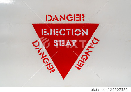 Ejection seat warning sign on an old aircraft fuselage close-up Ejection seat warning sign on an old aircraft fuselage close-up 129907582