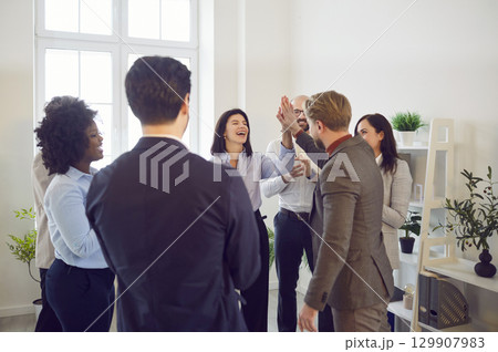 Happy colleagues giving high five at meeting at office, celebrating success or business achievement 129907983