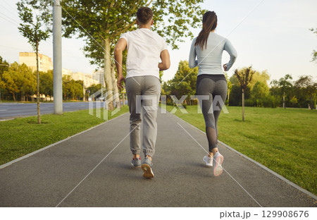 Sporty friendly couple, people actively running outdoors in green park, healthy looking jogging 129908676