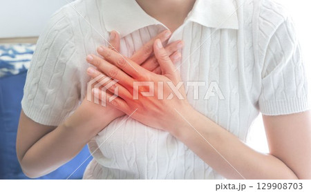 Heart failure. young woman pressing on chest with painful expression. Severe heartache, having heart attack or painful cramps, heart disease. people with heart problem concept. 129908703