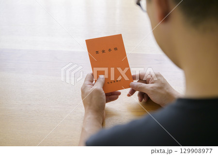 年金手帳を見つめる男性 年金手帳を見つめる男性 129908977