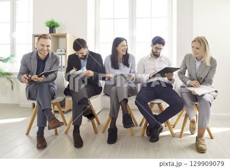 Business people sitting in a row during conference or seminar in office holding financial documents 129909079