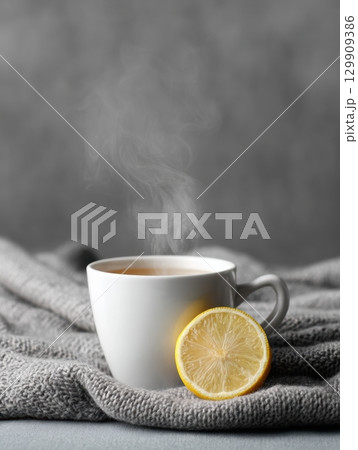 Warm Lemon and Honey Drink in a White Cup on a Cozy Grey Blanket With Rising Steam Creating a Comforting Atmosphere Warm Lemon and Honey Drink in a White Cup on a Cozy Grey Blanket With Rising Steam Creating a Comforting Atmosphere 129909386