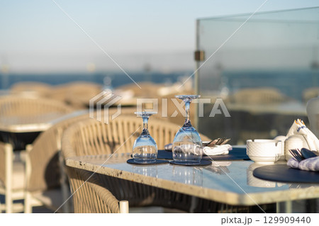Romantic dining setting by the sea, featuring elegant tables, glassware 129909440