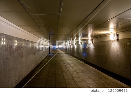 Long illuminated tunnel with glossy walls and soft lighting creating a mysterious atmosphere at night 129909451