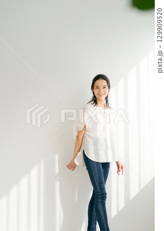 窓辺に立つデニムの女性（縦長） 129909520